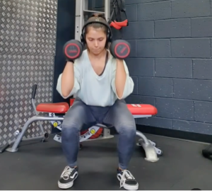 Kiri Quinn personal trainer doing shoulder squat press with dumbbells at the gym