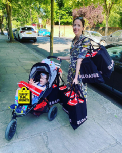 Lucy Herron pushing a pram while holding many bags and boxes of her small business